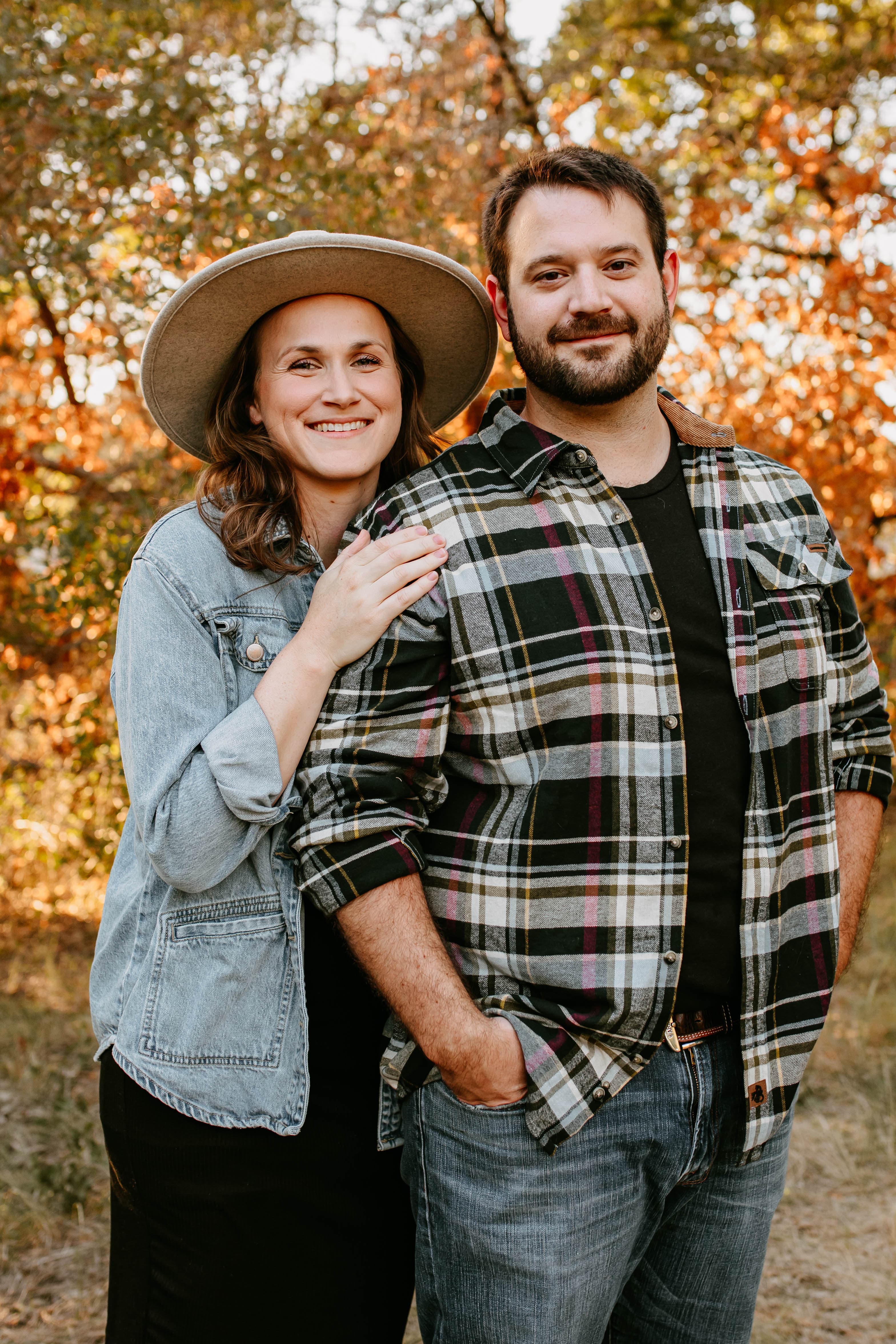 Good Soil Society's founders — a husband and wife — standing together outdoors among autumn trees