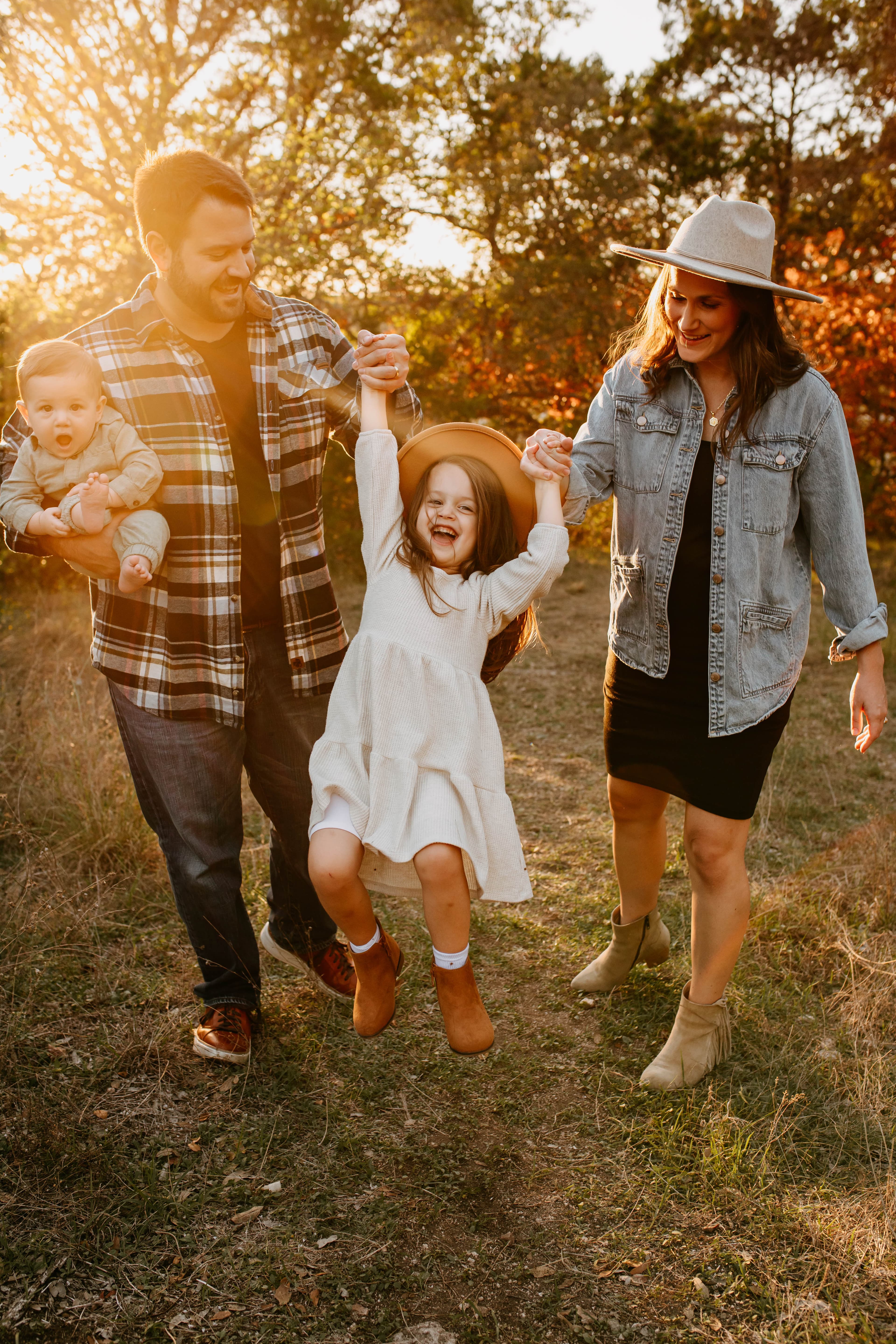 Good Soil Society's founders walking through a golden field at sunset, swinging their young daughter by the arms while the father holds their baby
